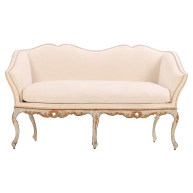 An Italian painted and carved settee, 18th C., in recent fabric.