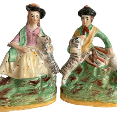 A pair of antique Staffordshire figurines, Man and woman in Scottish dress with lambs. English pottery Victorian figurines 