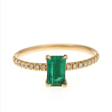 An emerald and diamond ring set with an emerald-cut emerald flanked by numerous brilliant-cut diamonds, mounted in 18k gold. Size 54. 