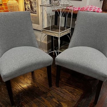 A pair of upholstered grey chairs with studded back. 20”x22”x37” 