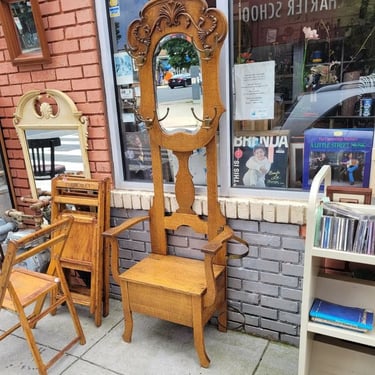 Early 20th Century Oak Hall Tree. Flip up seat for storage, clear beveled mirror, four brass hat/coat hooks, umbrella holder.…