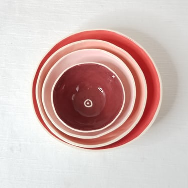 Set of 4 small nesting ceramic dishes in red, pink, peach, & maroon 