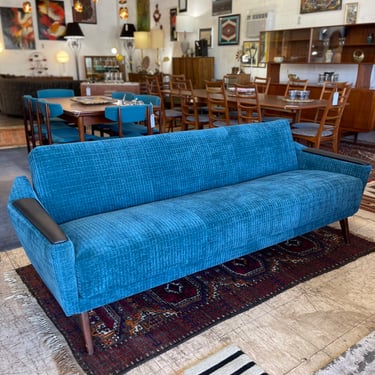 Mid Century Convertible SofaCommonly known as a &#8216;click clack&#8217; sofa when it converts to a bed. Sofa has been newly upholstered in a soft aqua patterned fabric with new foam. Armrests also have new black vinyl.