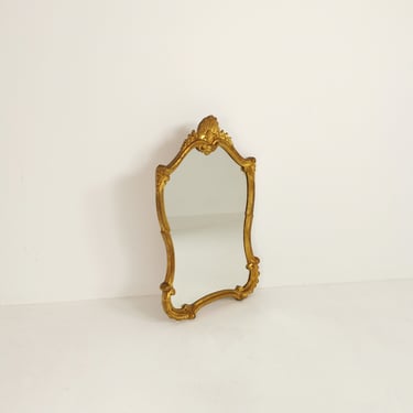 Classic style mirror in gold leaf with shaped frame  Italy 1980s. 