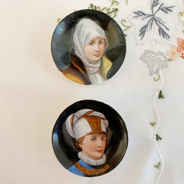 A vintage pair of miniature porcelain portrait butter pats, small hand painted plates with girl & boy wearing fancy hats 